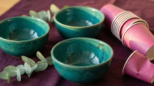 Three well-crafted teal ceramic bowls beside a stack of flimsy mass-produced magenta paper cups, symbolising effective focused strategies versus overwhelming generic plans.